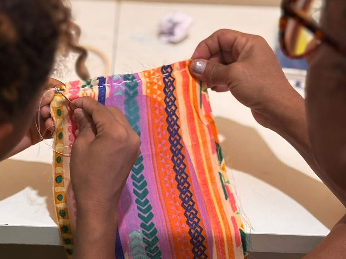 Mãos de acolhida costurando na oficina de artesanato